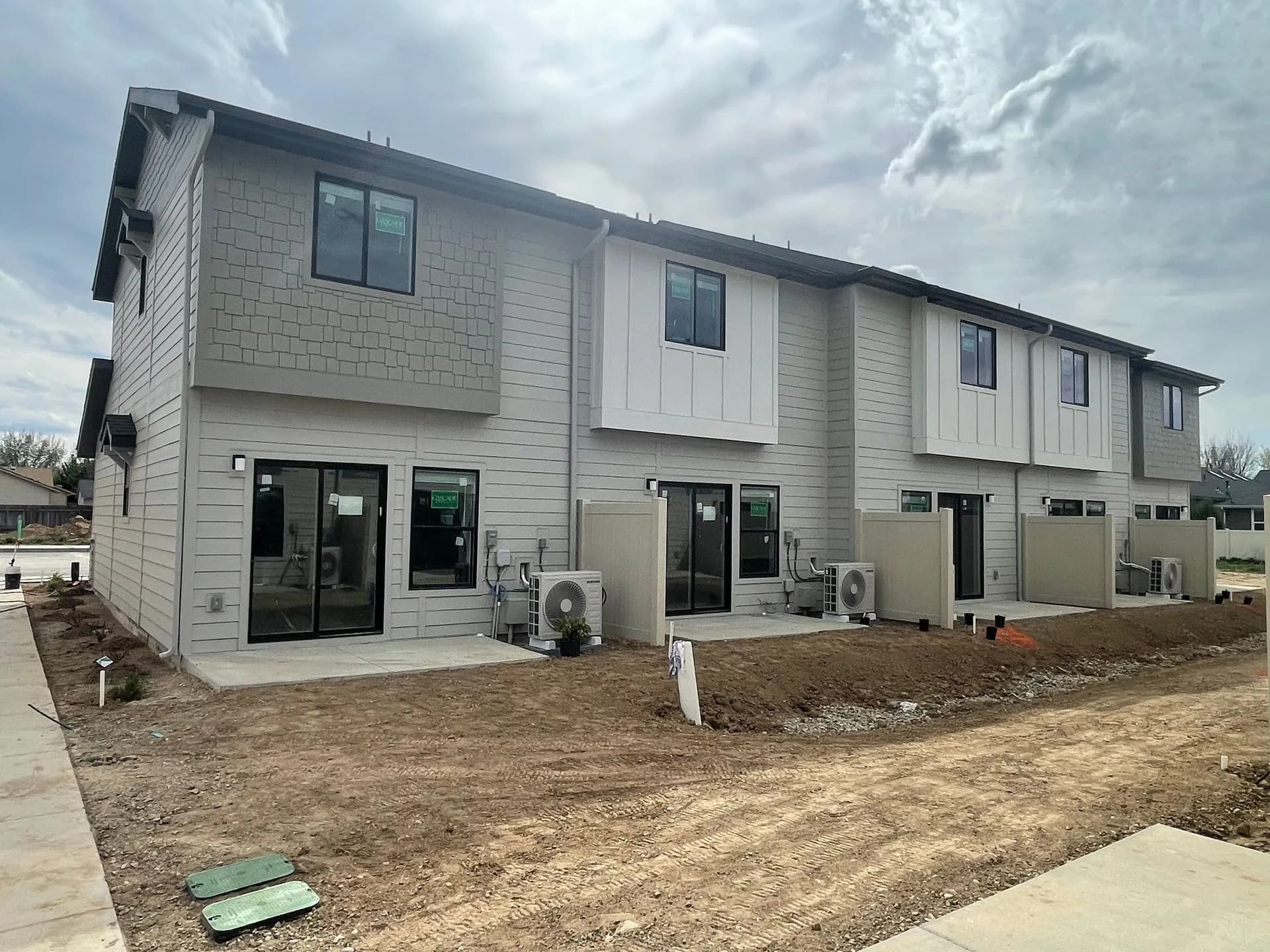 Rear view of townhomes showing private cement patios and individual HVAC units